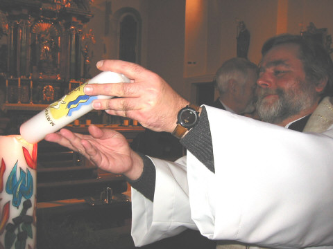 Pfarrer Dekwart zündet die Taufkerze an